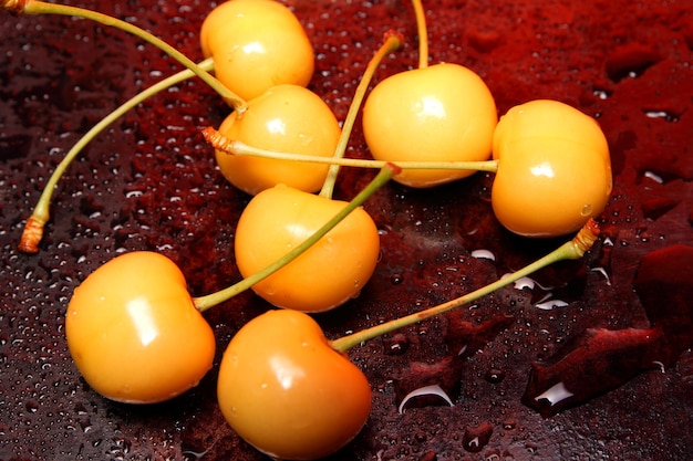 Healthy food concept Yellow cherry with drops of water on a black background View from above Closeup of sweet berries