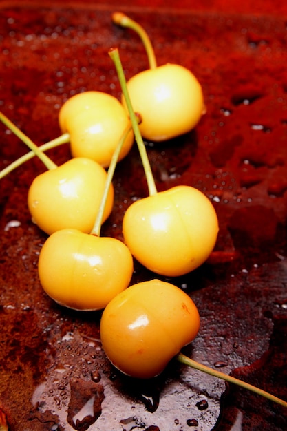 Foto concetto di cibo sano giallo ciliegia con gocce d'acqua su sfondo nero vista dall'alto alzato di dolci frutti di bosco