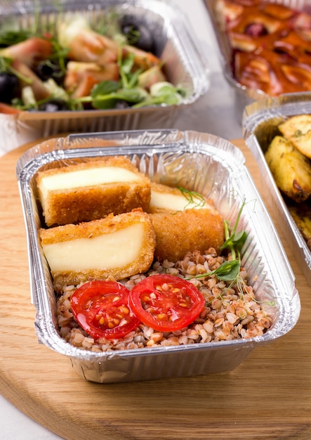 Healthy food delivery. Buckwheat porridge in a container with vegetables and micro greens and cheese