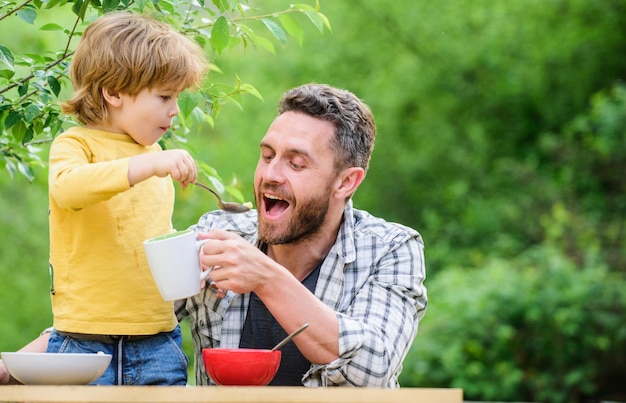 Healthy food and dieting childrens day happy fathers day little
boy with dad eat cereal father and son eating outdoor family dinner
time summer picnic morning breakfast family bonding time