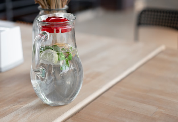 Healthy food and drinks. Water in glass mug with lemon and mint on wooden table in cafe. A refreshing summer drink. Lemonade