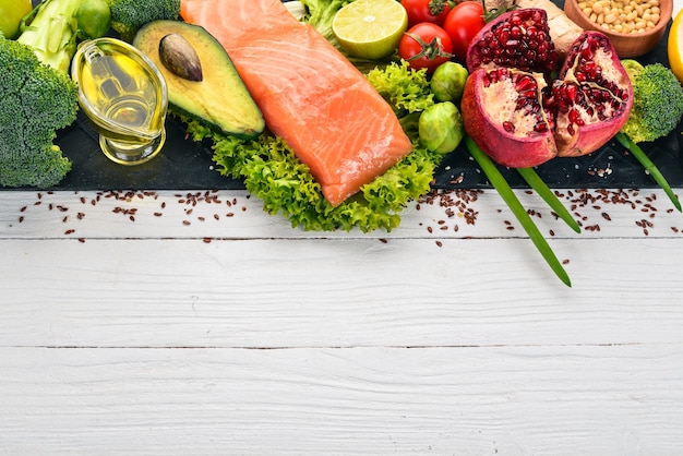 Healthy food Fish salmon avocado broccoli fresh vegetables nuts and fruits On a white wooden background Top view Copy space