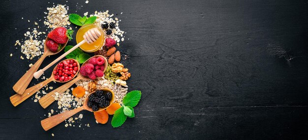 Healthy food Fresh wild berries copper nuts oatmeal dried fruits and seeds On a wooden background Top view Free space for text
