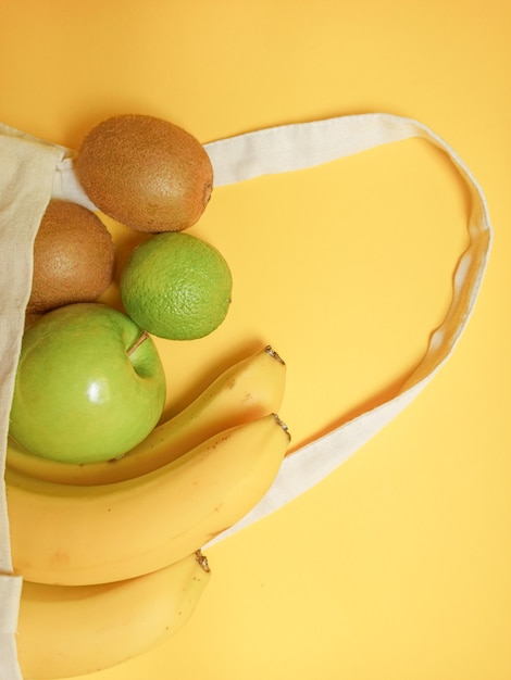 Здоровая пища. Здоровые фрукты в натуральной сумке на желтом.