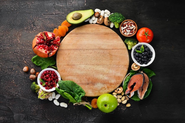 Healthy food for the heart Fish blueberries nuts pomegranate avocados tomatoes spinach flax On a dark background Top view Free space for your text