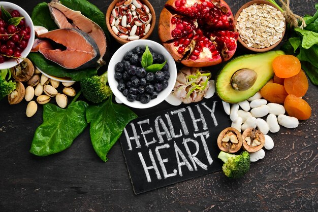 Healthy food for the heart Fish blueberries nuts pomegranate avocados tomatoes spinach flax On a dark background Top view Free space for your text