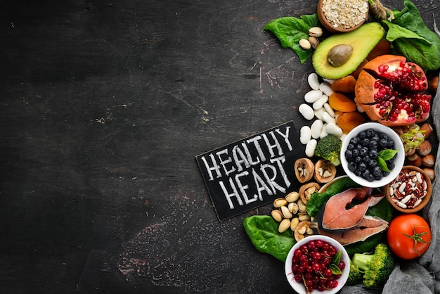 Healthy food for the heart Fish blueberries nuts pomegranate avocados tomatoes spinach flax On a dark background Top view Free space for your text