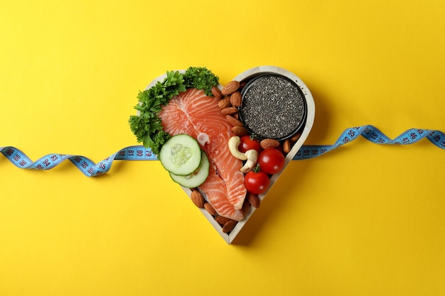 Photo healthy food in heart and measuring tape on yellow background