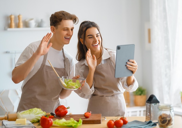自宅で健康的な食事幸せな愛情のあるカップルは、キッチンで適切な食事を準備しています