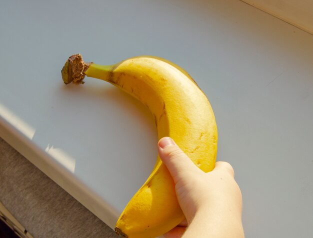 Healthy food for kids. Children's hand holding a banana