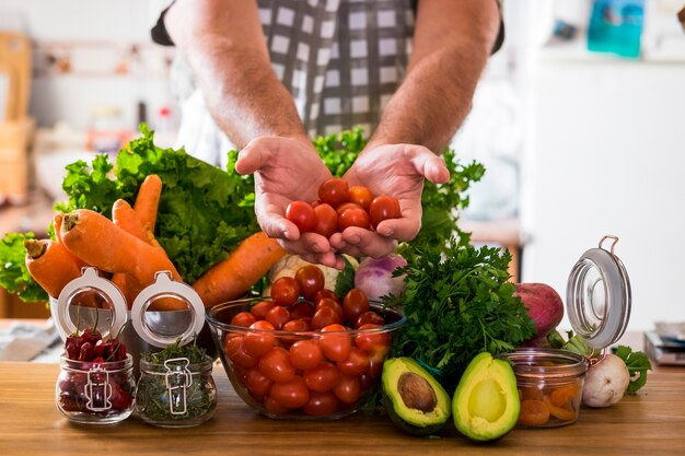 Healthy food lifestyle with man and mixed vegetables and avocado on a wooden table