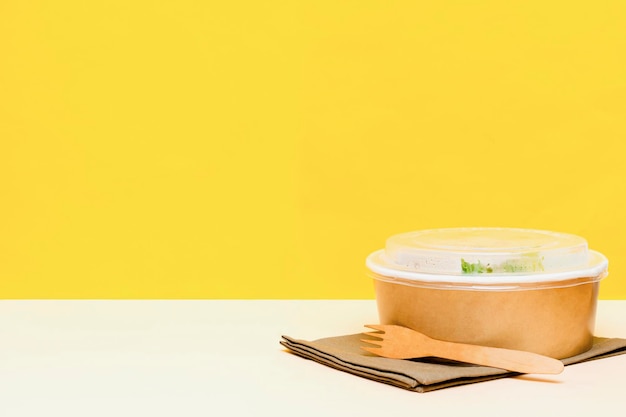 노란색 배경에 크래프트 종이 상자 환경 친화적인 상자 일회용 그릇 포장 용기에 있는 건강식 점심. 닭고기, 계란, 쌀, 채소. 배달을 테이크 아웃하십시오. 환경 보호 복사 공간