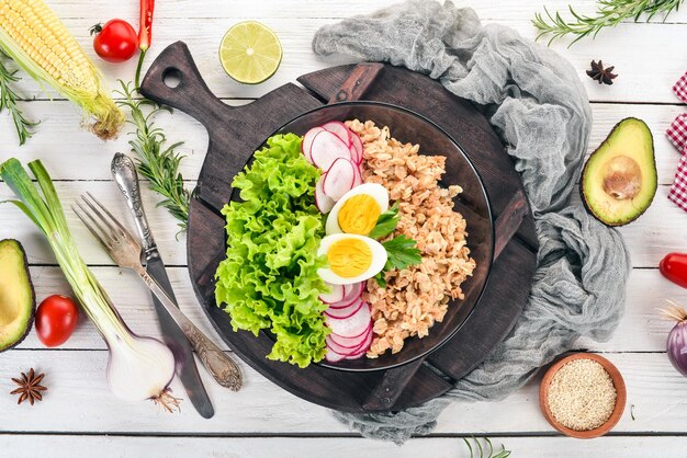 Healthy food Oatmeal lettuce radish egg On a wooden background Top view Free copy space