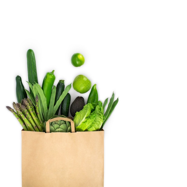 Healthy food in paper bag, fresh green vegetables insolated on white.