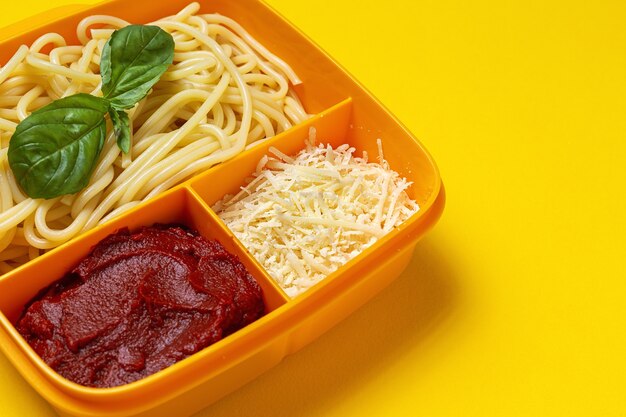 Healthy Food in Plastic containers ready to eat with homemade spaghetti with tomato, cheese and basil on the work table. Italian food. To take away.