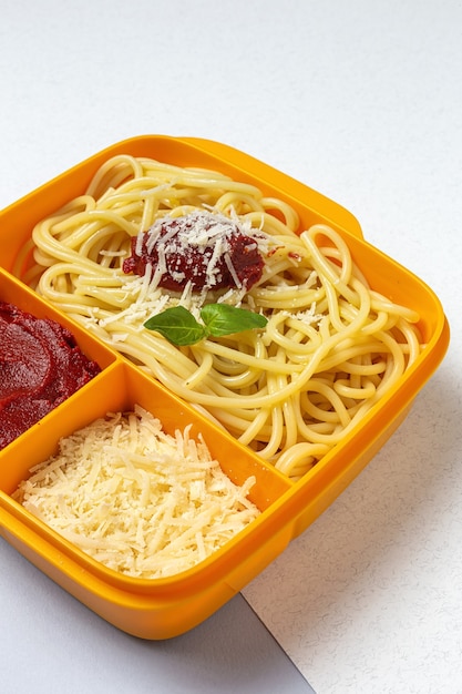 Healthy Food in Plastic containers ready to eat with homemade spaghetti with tomato, cheese and basil on the work table. Italian food. To take away.