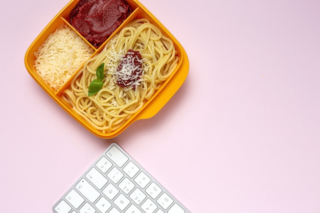 作業台にトマト、チーズ、バジルを添えた自家製スパゲッティと一緒にすぐに食べられるプラスチック容器に入った健康食品。イタリア料理。持ち帰る。