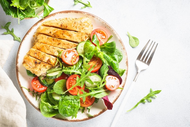 Healthy food plate on white Green salad with roasted chicken fillet Top view with copy space