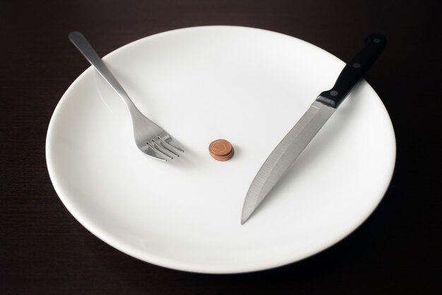 Foto cibo sano, povertà, risparmio di denaro monete su un piatto bianco.