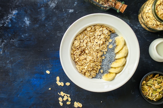 healthy food smoothie bowl, oatmeal, chia seeds on dark concrete background