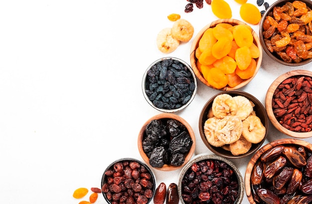 Photo healthy food snack natural sun dried fruits mix in bowls on white background top view