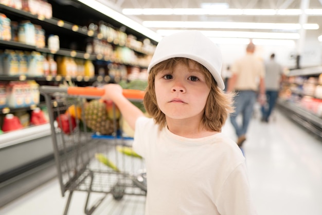 食料品店や面白い小さなスーパーマーケットの肖像画で子供男の子と若い家族のための健康食品