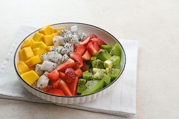 Healthy fresh fruit salad bowl dragon fruit kiwi mango strawberry on the table Selected focus