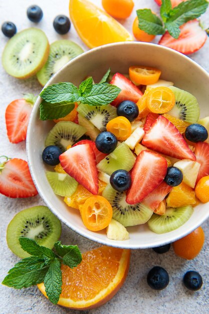 Healthy fresh fruit salad in a bowl on wooden background