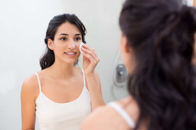 Здоровая свежая девушка удаляет макияж с лица ватным диском