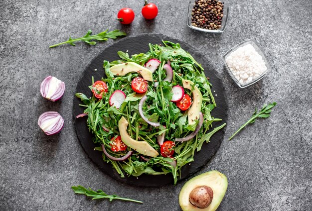 Insalata di verdure fresche sane pomodori rucola avocado ravanello su uno sfondo di pietra