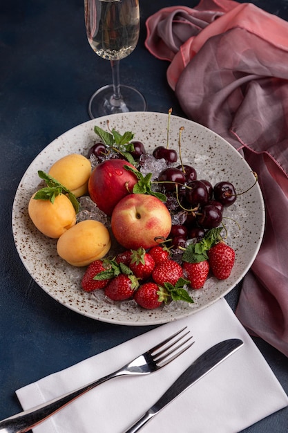 Healthy fruit platter strawberries apples peaches apricots on a dark gray wooden table top view closeup selective focus