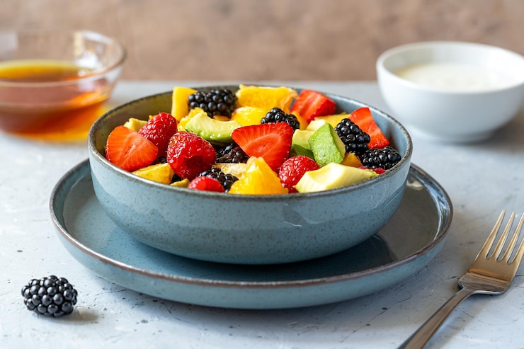 Photo healthy fruit salad in a grey bowl made with avocado strawberry raspberry orange blackberry peaches