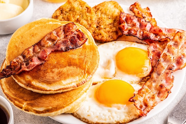 Photo healthy full american breakfast with eggs bacon pancakes and latkes, selective focus.