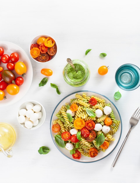 Healthy fusilli pasta with pesto sauce, roasted tomatoes, mozzarella