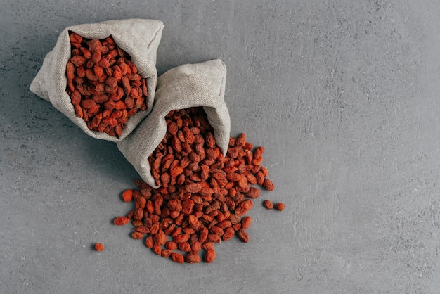 Healthy goji berries spilled out of small sack isolated over grey background Agriculture and nutrition concept Superfood