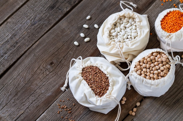 Healthy grains and groats in linen eco bags on wooden table