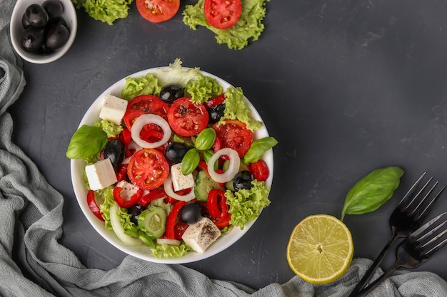 Healthy Greek salad of lettuce, tomato, onion, pepper, cheese, olives, basil, cucumbers and oil