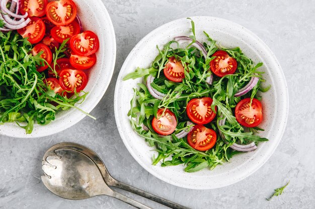 위에서 토마토와 붉은 양파 보기와 건강한 녹색 신선한 Arugula 샐러드 그릇