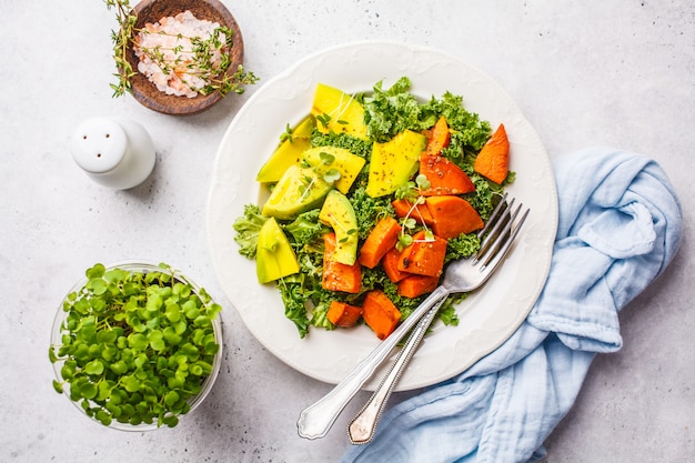 Healthy green kale salad with avocado and baked sweet potatoes.