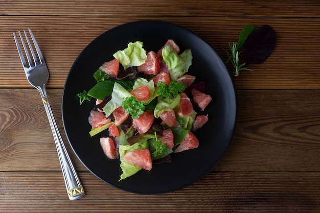 Healthy green salad with grapefruit, lose weigh food. Diet plan. Wooden rustic table.