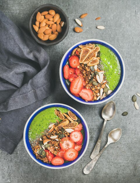 Healthy green smoothie breakfast bowls with granola fruit seeds almonds