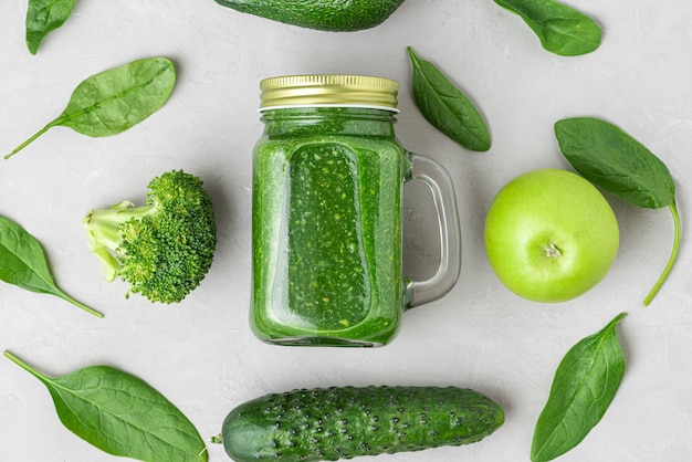 Healthy green smoothie in a jar to take away made of spinach, broccoli, avocado, apple and cucumber. top view. flat lay. Raw vegan food concept