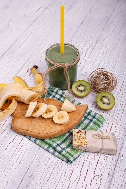 healthy green smoothie with bananas and kiwi lie on the table