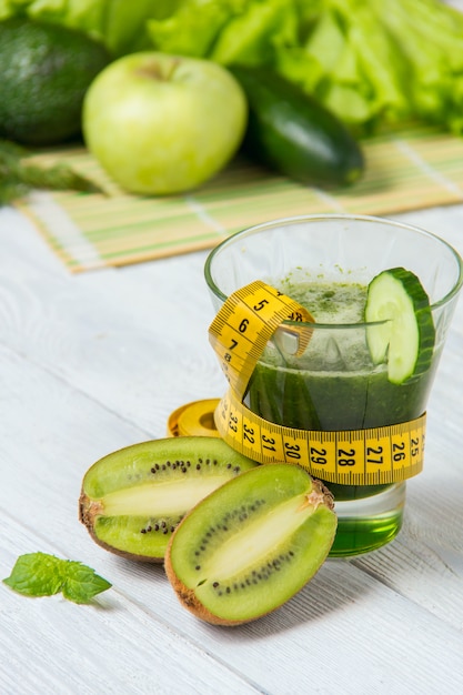 Healthy green smoothie with ingredients on white wooden background