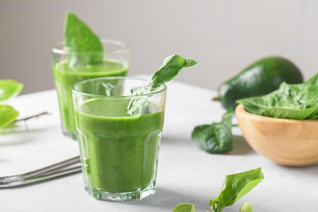 Healthy green smoothie with spinach avocado banana and vegan milk in two glasses and fresh