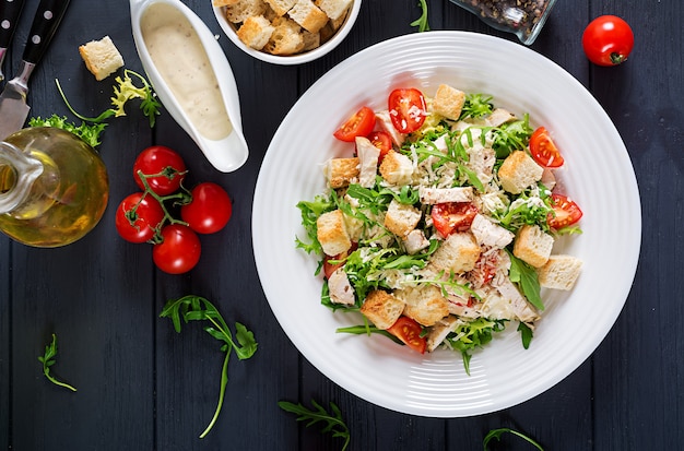 Фото Полезный куриный салат цезарь на гриле с помидорами, сыром и гренками.