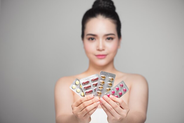 Healthy happy asian woman with pills in hand.