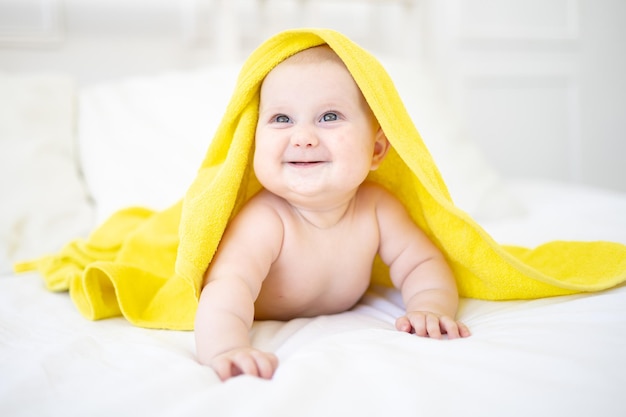 A healthy happy cute baby is lying on his stomach after bathing in a towel and smiling