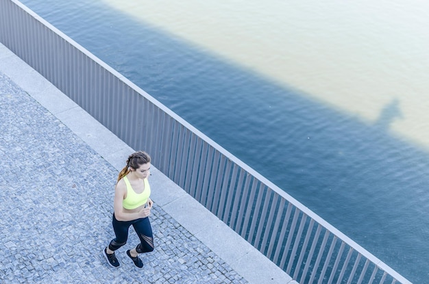 Foto donna felice e sana che fa jogging, corre all'aperto e ascolta musica