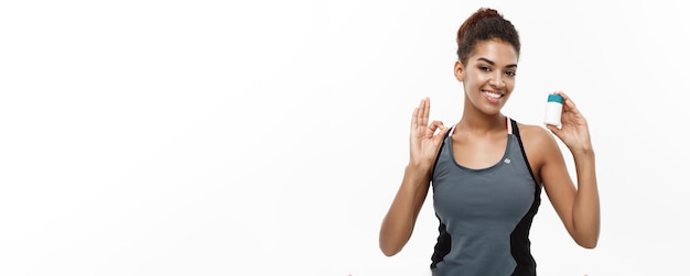 Healthy and healthcare concept portrait of beautiful sporty african american holding bottle of supp